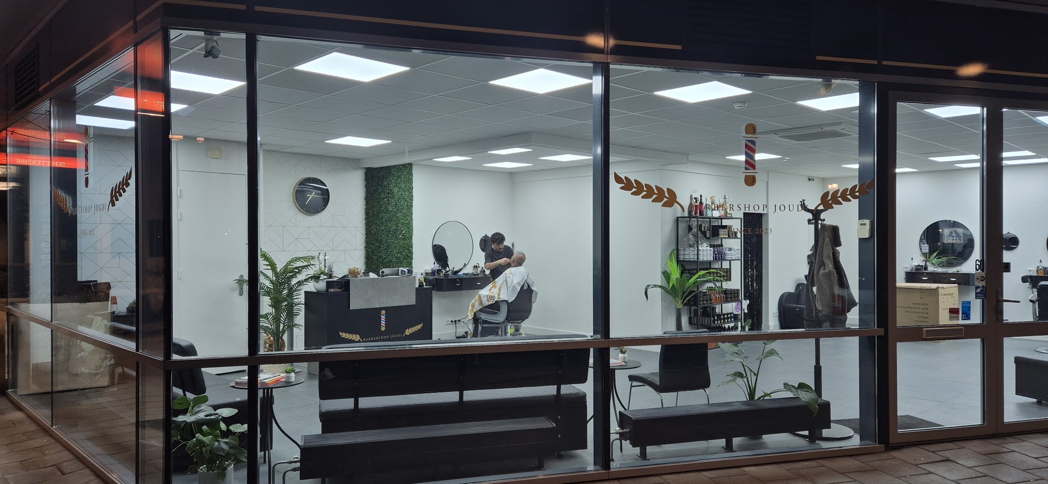 De verlichte gevel van Barbershop Joudi in de avond